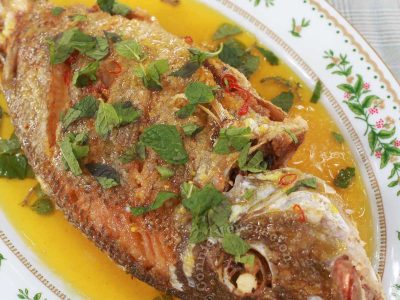 Fried whole fish with lemon sauce garnished with mint leaves