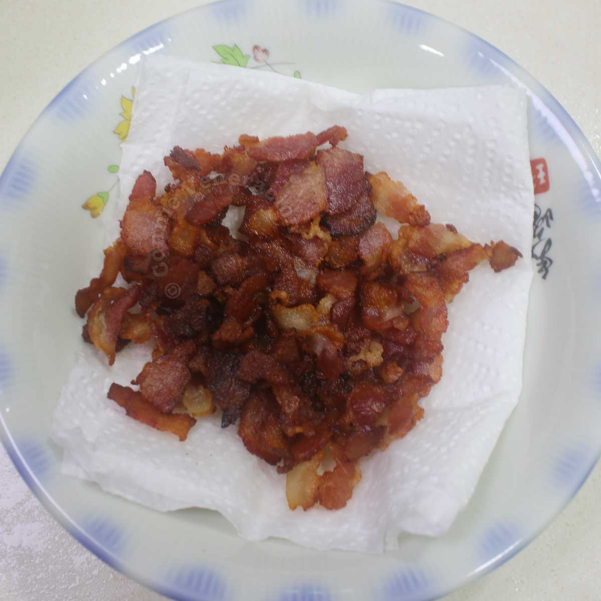 Chopped bacon in bowl lined with paper towel