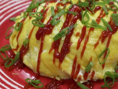 Omurice (omelette rice) drizzled with ketchup and sprinkled with scallions