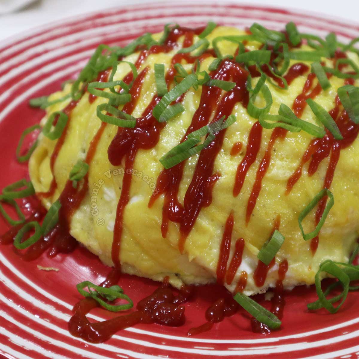 Omurice (omelette rice) drizzled with ketchup and sprinkled with scallions