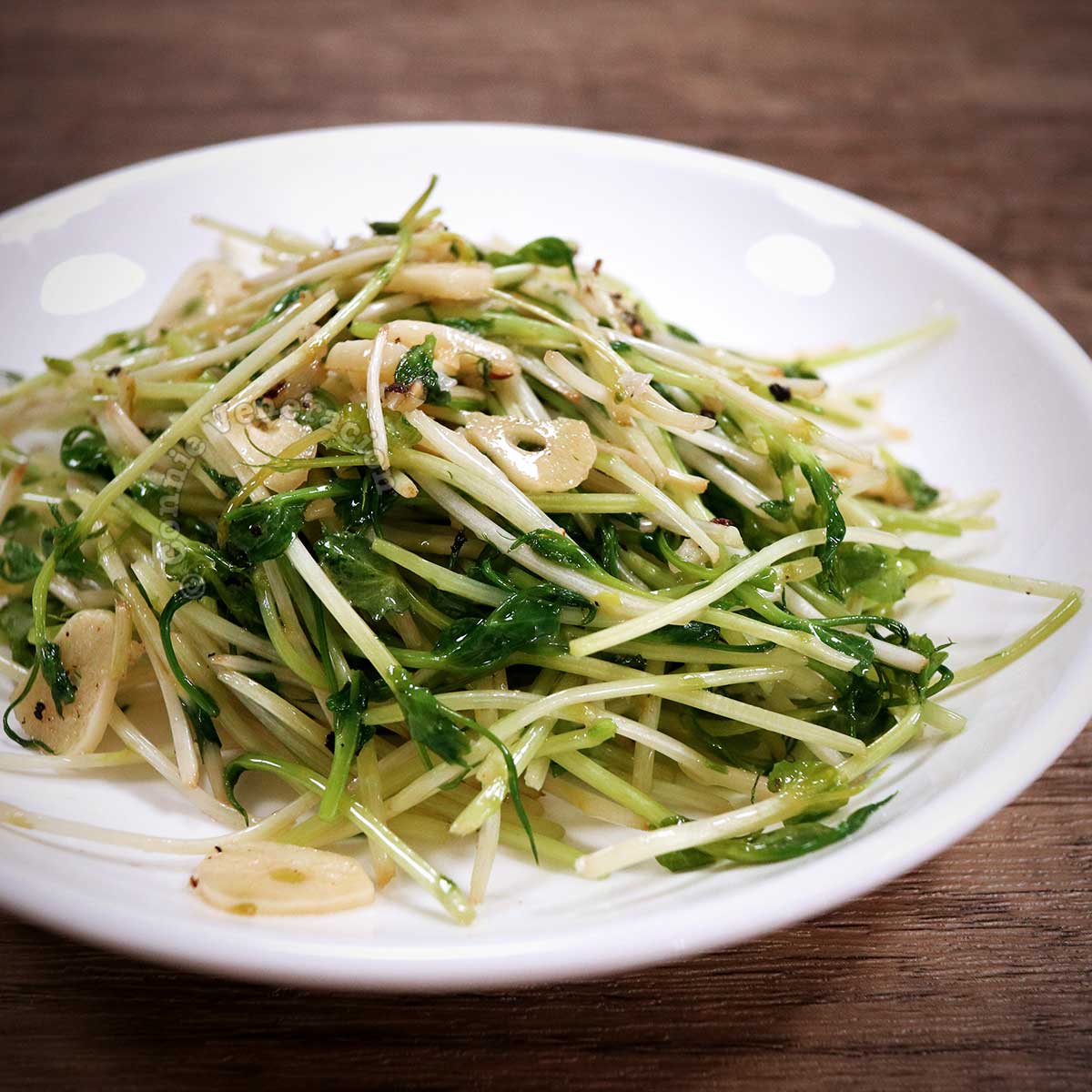 Sauteed pea shoots and garlic on white plate
