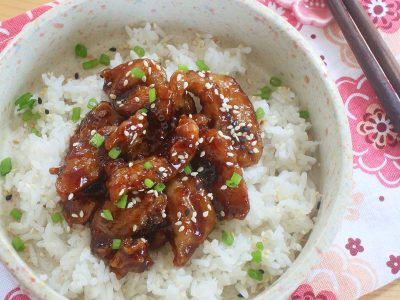 Sesame chicken sprinkled with scallions served over rice