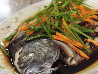 Steamed pompano with black bean garlic sauce garnished with julienned carrot and scallions