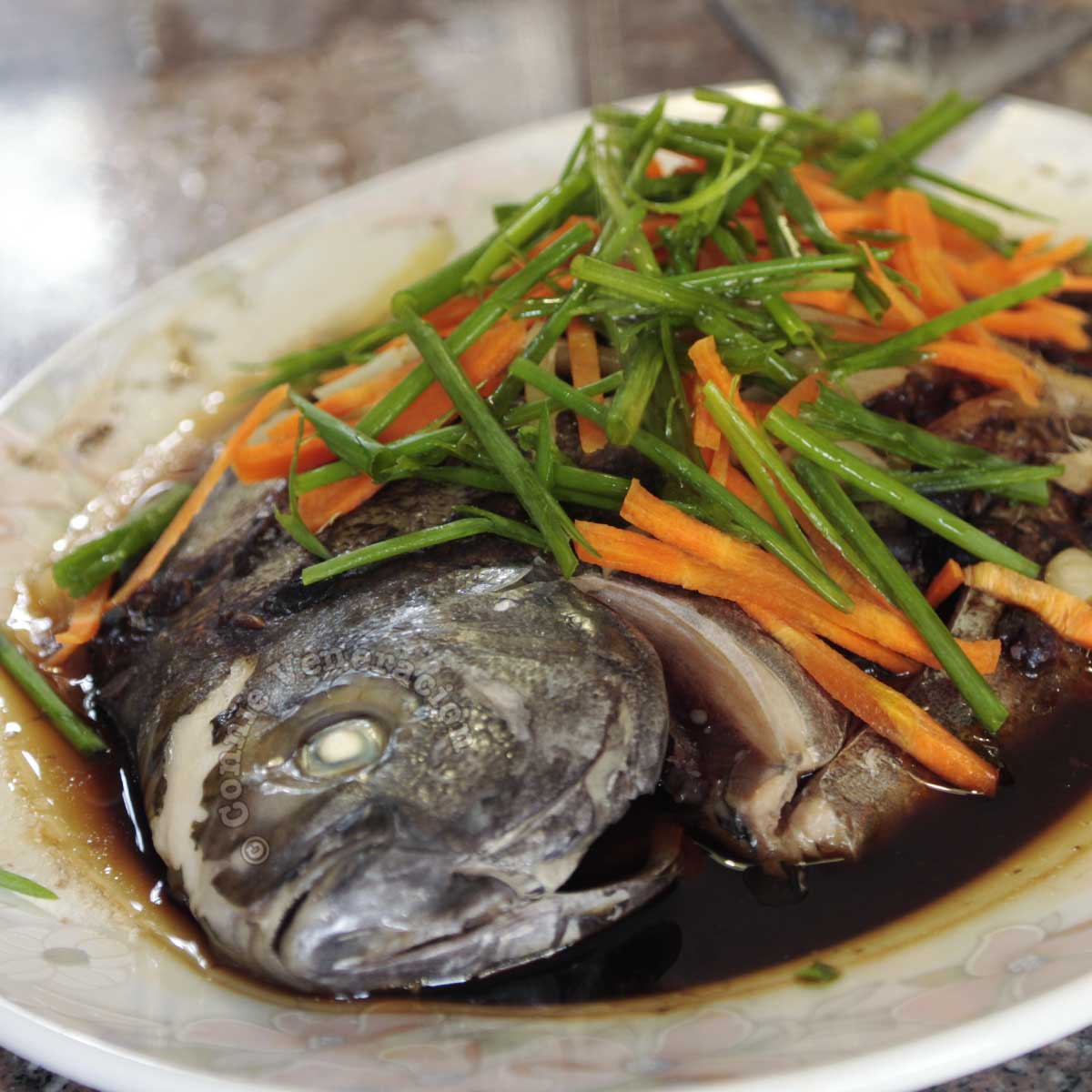 Steamed pompano with black bean garlic sauce garnished with julienned carrot and scallions
