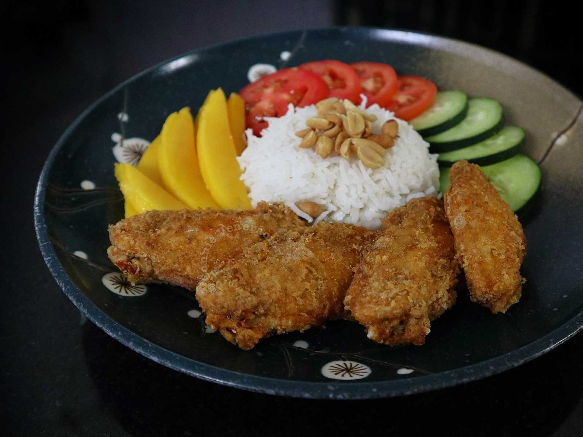 Thai fried chicken wings with rice,, mangoes, tomatoes and cucumber