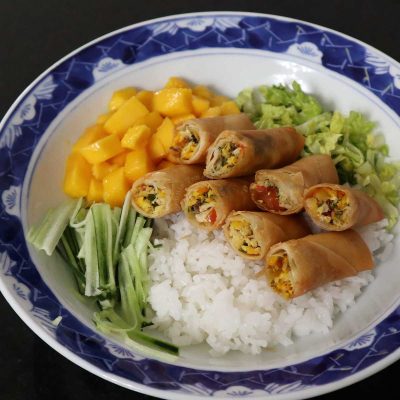 Smoked fish, salted eggs and tomato spring rolls with rice, mangoes and vegetables in bowl