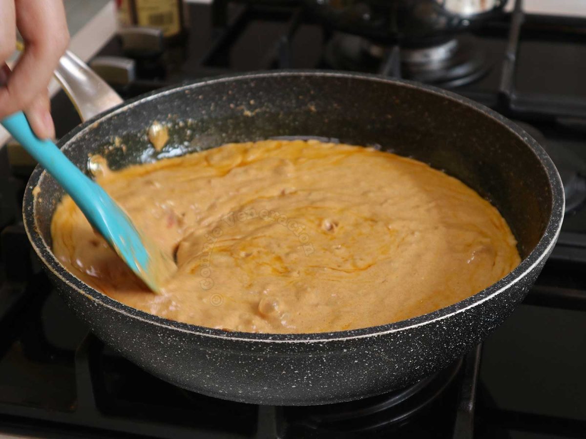 Mixing browned onion, tomatoes and cream in pan