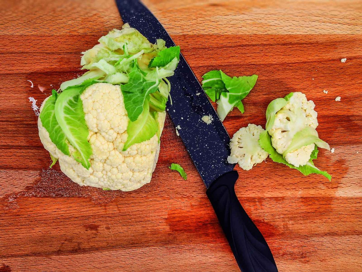 Cauliflower snd florets on choppong board with knife