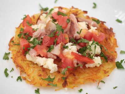 Rosti (Swiss fried grated potatoes) topped with tomatoes, crumbled feta and chopped smoky ham