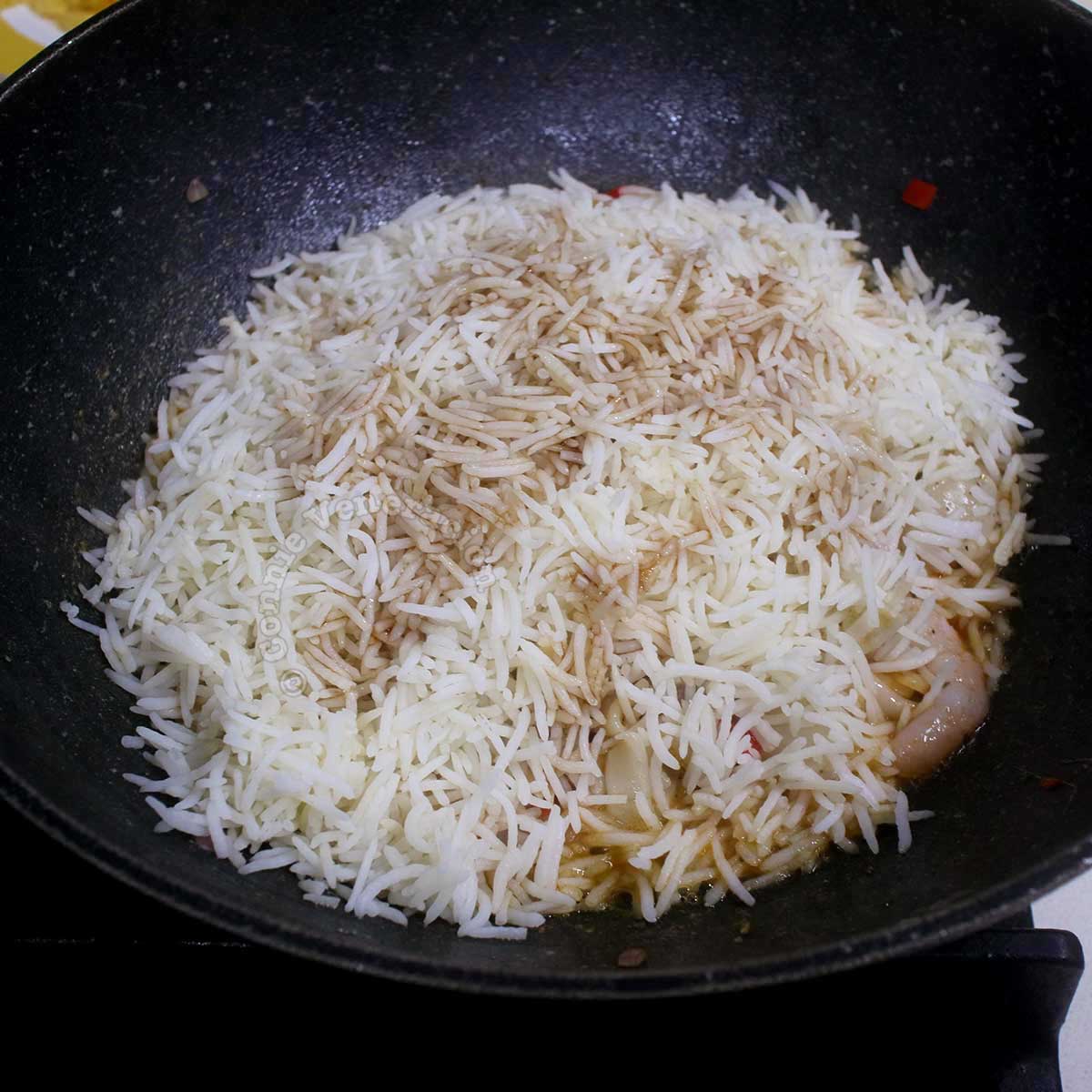 Rice drizzled with seasoning in wok