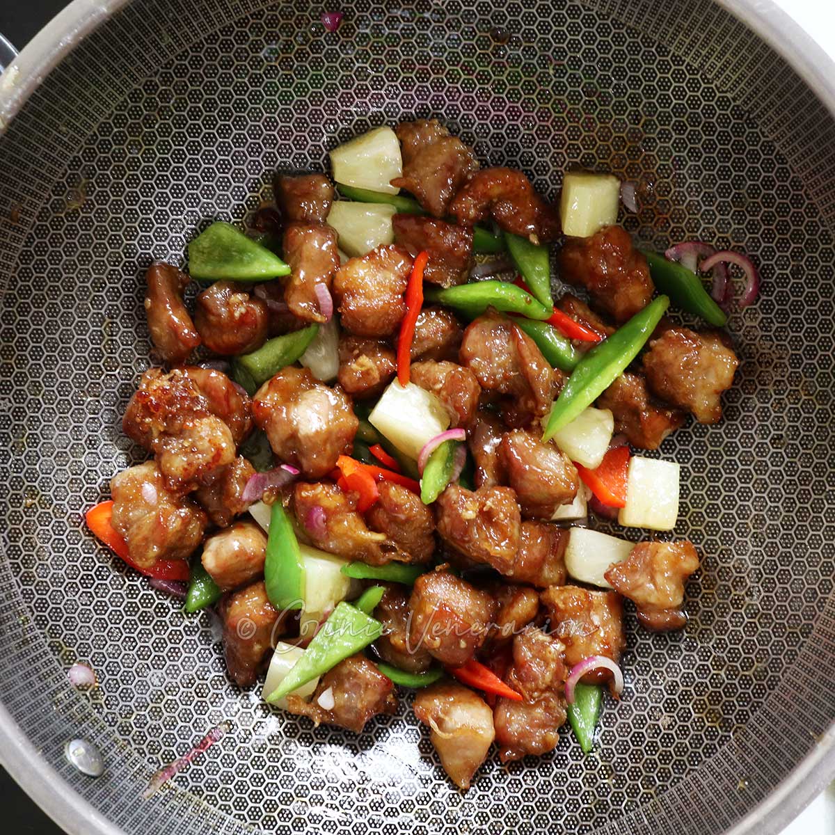 Sweet sour pork with pineapple chunks and vegetables in wok