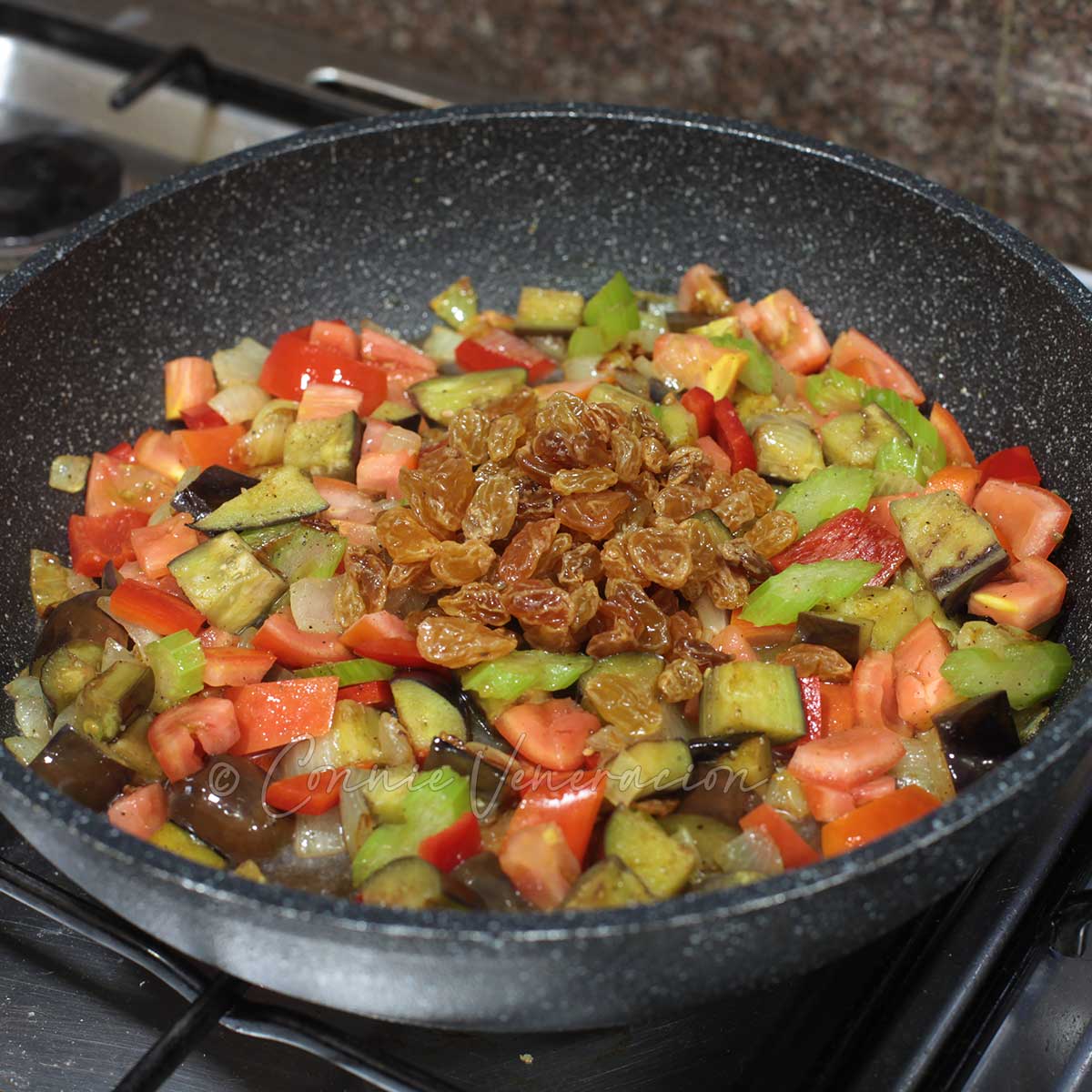 Adding vinegar and raisins to vegetables in pan to make caponata