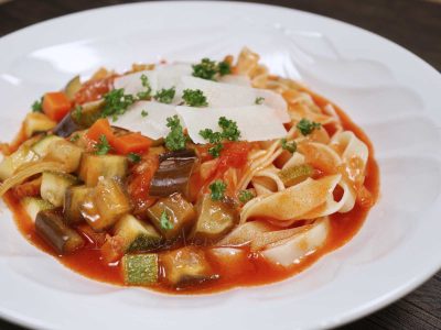 Minestrone served with pasta and topped with shaved Pecorino and parsley