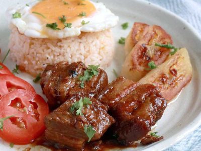 Filipino pork adobo with rice, egg, tomatoes and fried saba bananas