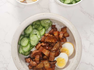Taiwanese braised pork belly served over rice with pickled cucumber and halved egg on the side
