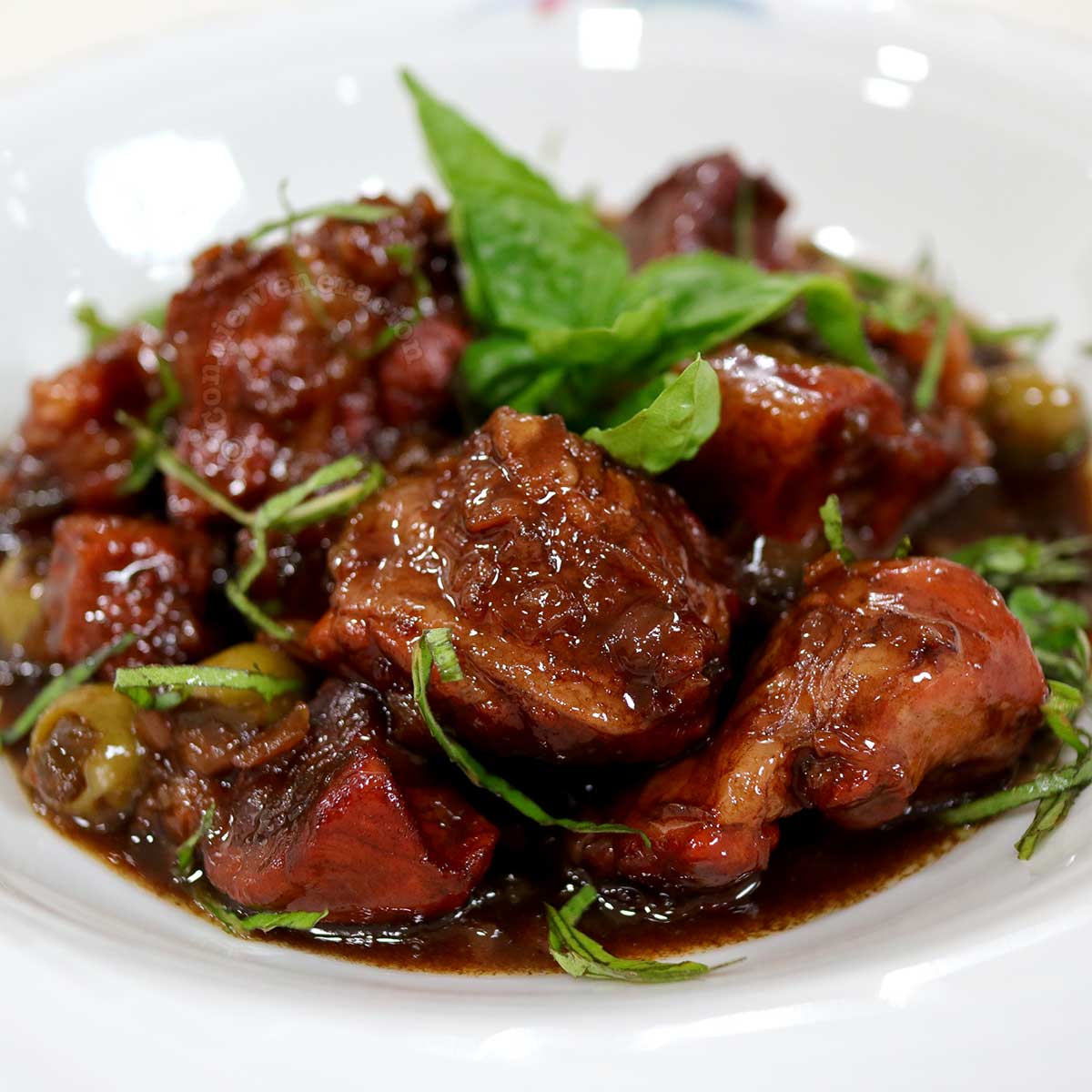 Italian-style sweet and sour pork stew (spezzatino agrodolce) garnished with basil