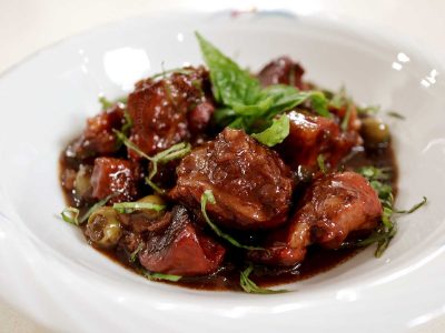 Italian-style sweet and sour pork stew (spezzatino agrodolce) garnished with basil