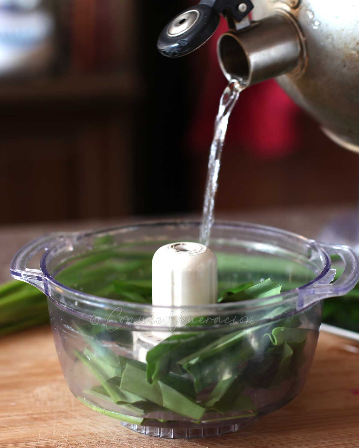 Pouring hot water over pandan leaves in food processor