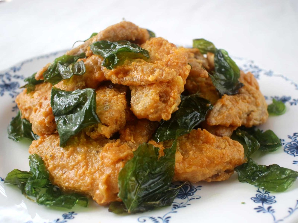 Fried chicken wings with salted duck egg yolk sauce garnished with crispy Thai basil