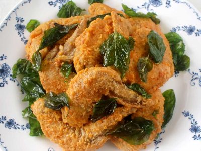 Fried chicken wings with salted duck egg yolk sauce garnished with crispy Thai basil