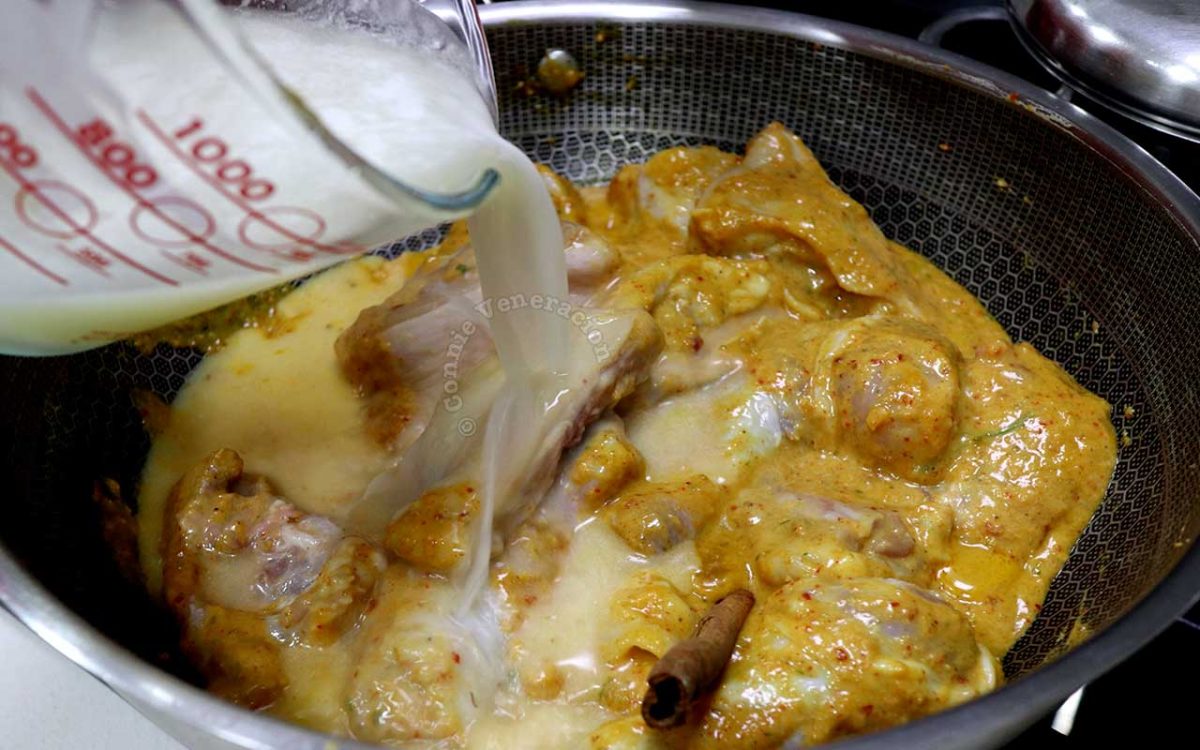 Adding coconut cream to Thai chicken curry during the last stage of cooking