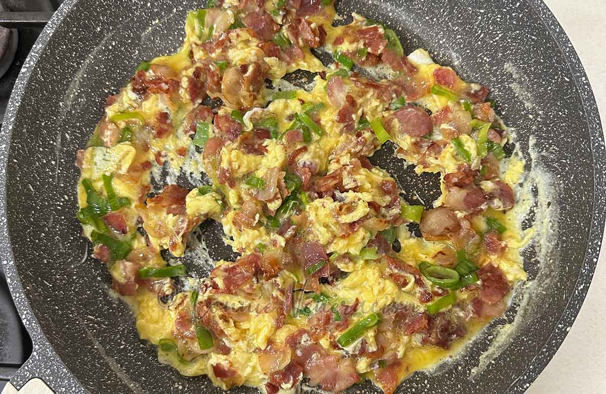 Scrambled eggs, bacon and scallions in pan