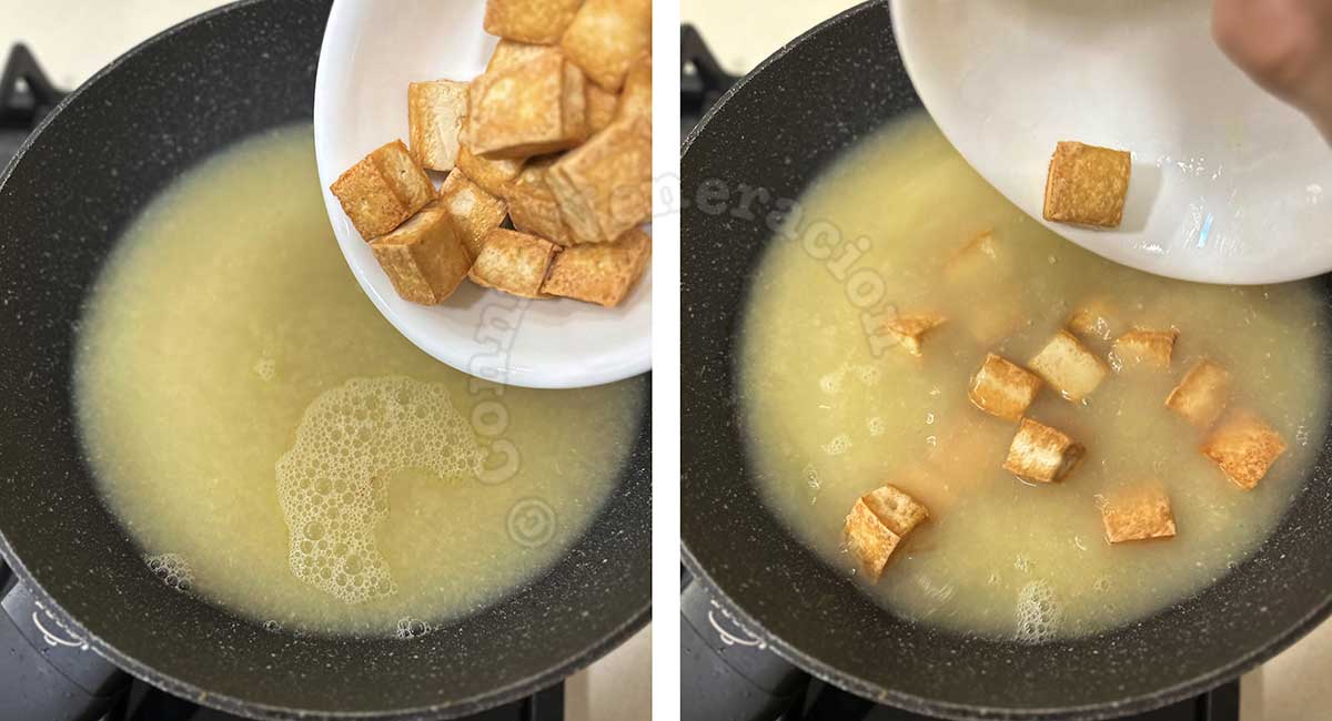 Adding fried tofu cubes to simmering broth in pan