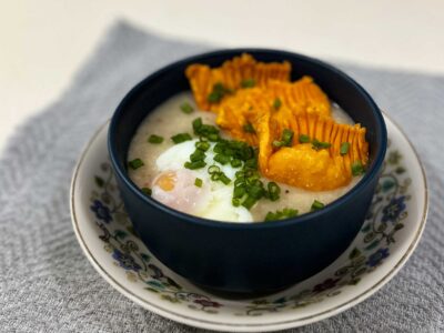 Congee with onsen egg and fried shrimp dumplings in dark blue bowl