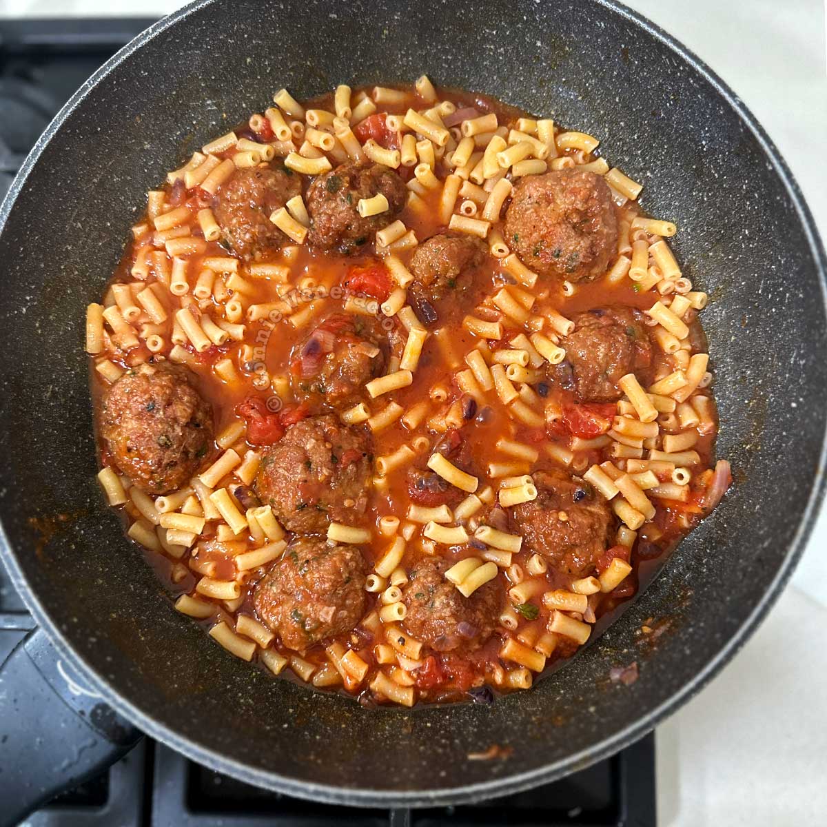 Macaroni and meatballs simmering in tomato sauce