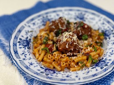 Meatballs and macaroni garnished with cheese and basil