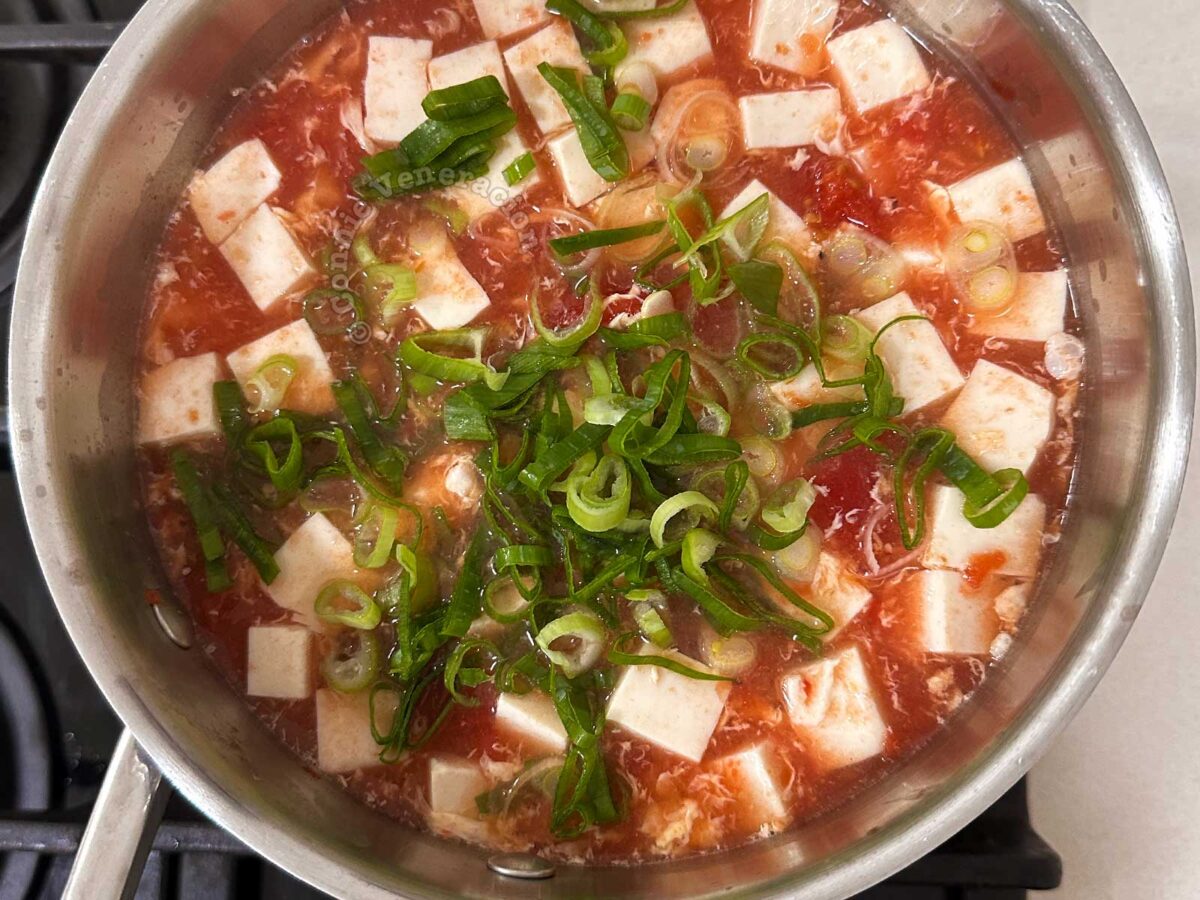 Tofu and tomato egg drop soup garnished with scallions
