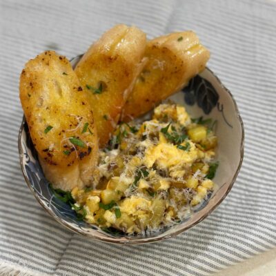 Potato and egg breakfast with buttered toast garnished with grated pecorino