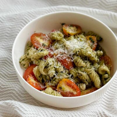 Homemade pasta with pesto and cheery tomatoes topped with grated Pecorino